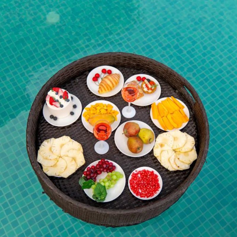 Exquisite Floating Breakfast at Villa Miraan – Villa Near Lakhawali Lake Wicker tray filled with fresh fruits, pastries, and drinks floating in a blue swimming pool at a villa near Lakhawali Lake.