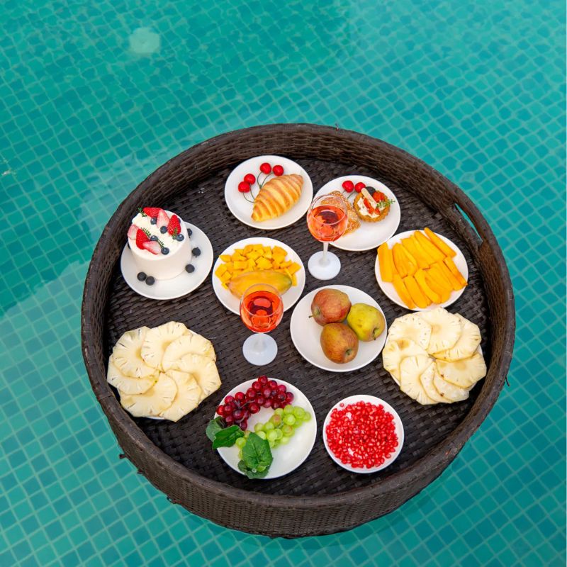 Luxurious Floating Breakfast at Villa Miraan – 9 BHK Villa Udaipur Wicker tray filled with fresh fruits and pastries floating in a pool at a 9 BHK villa Udaipur.