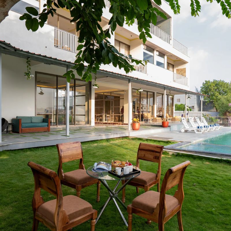 Outdoor Lawn Dining at Villa Miraan – Large Group Villa with Pool Udaipur Breakfast table setup on a green lawn overlooking the swimming pool at a large group villa with pool Udaipur.