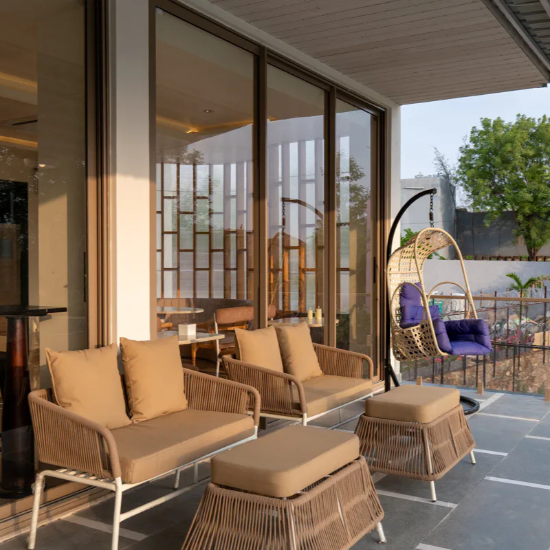Shaded Outdoor Patio at Villa Miraan – Villa Near Lakhawali Lake Comfortable woven outdoor furniture and a hanging swing chair on a patio at a villa near Lakhawali Lake.