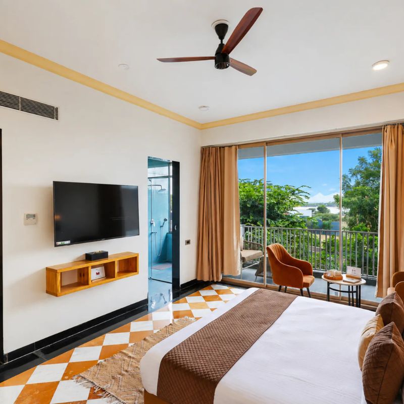 villa-miraan-udaipur-master-bedroom Spacious master bedroom with orange velvet bed and balcony view at Villa Miraan Udaipur